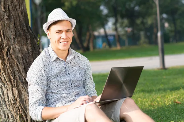 Ung man som arbetar i parken med en bärbar dator — Stockfoto