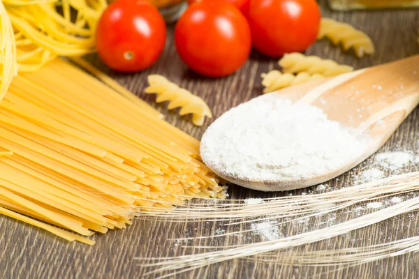 Pasta, tomatoes and flour on the spoon — Stock Photo, Image