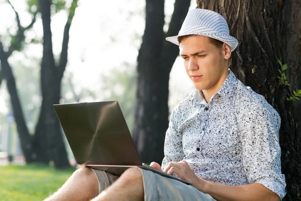 Young man working in the park with a laptop — Stock Photo, Image