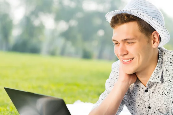 Jovem trabalhando no parque com um laptop — Fotografia de Stock