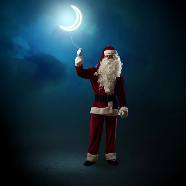 Papai Noel segurando uma lua brilhante — Fotografia de Stock