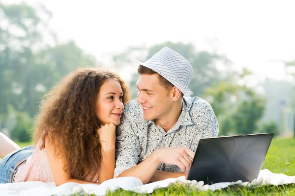 Coppia sdraiata insieme in un parco con laptop — Foto Stock