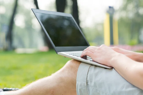Anak muda yang bekerja di taman dengan laptop — Stok Foto
