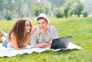 Çift birlikte parkta laptop ile yalan