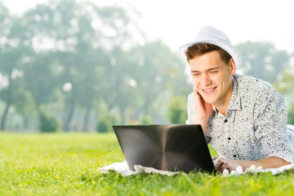 Νεαρός άνδρας που εργάζεται στο πάρκο με ένα φορητό υπολογιστή — Φωτογραφία Αρχείου