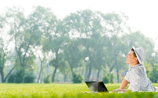 Молодий чоловік працює в парку з ноутбуком — стокове фото
