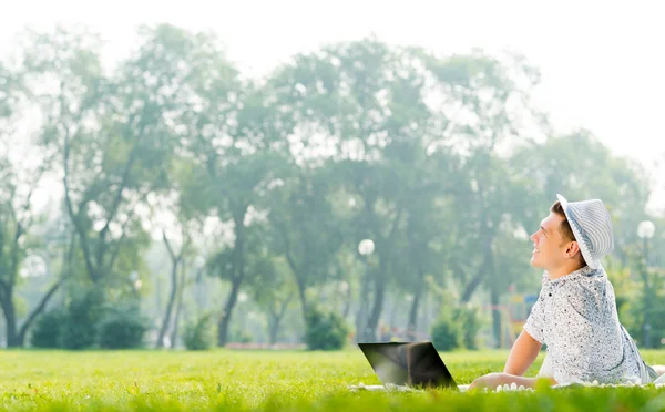 Jeune homme travaillant dans le parc avec un ordinateur portable — Photo