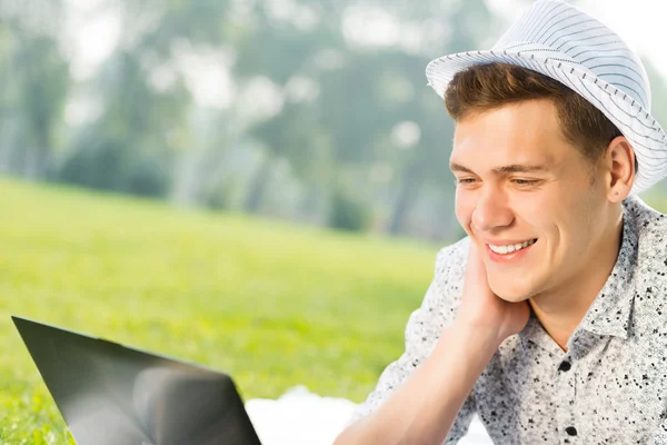 Young man working in the park with a laptop — Stock Photo, Image