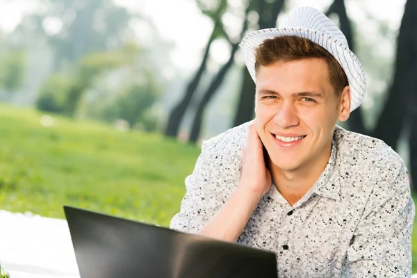 Jeune homme travaillant dans le parc avec un ordinateur portable — Photo