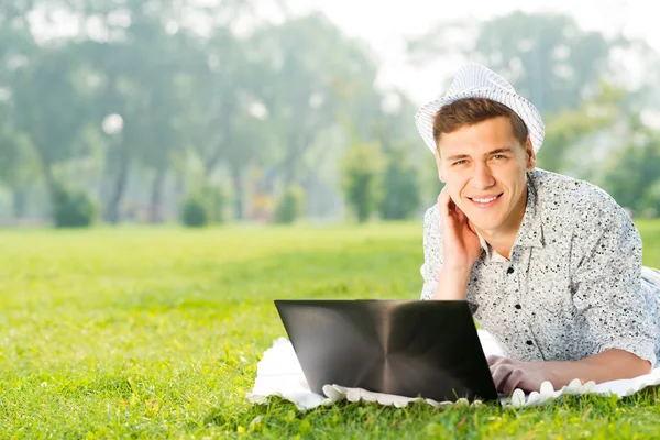 Jovem trabalhando no parque com um laptop — Fotografia de Stock