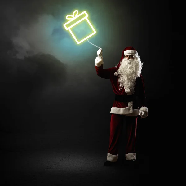 Weihnachtsmann hält ein leuchtendes Geschenk in der Hand — Stockfoto