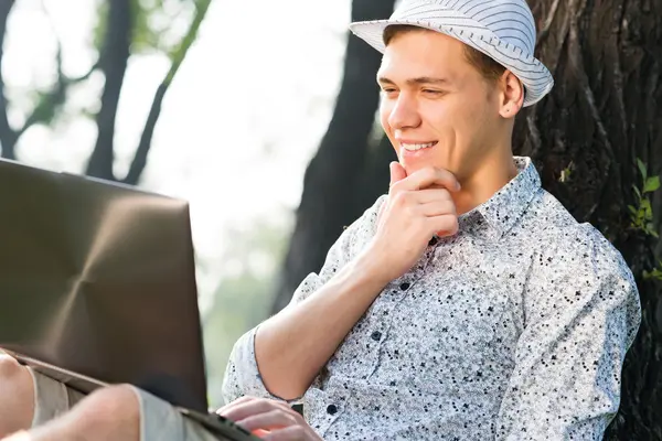 Ung man som arbetar i parken med en bärbar dator — Stockfoto