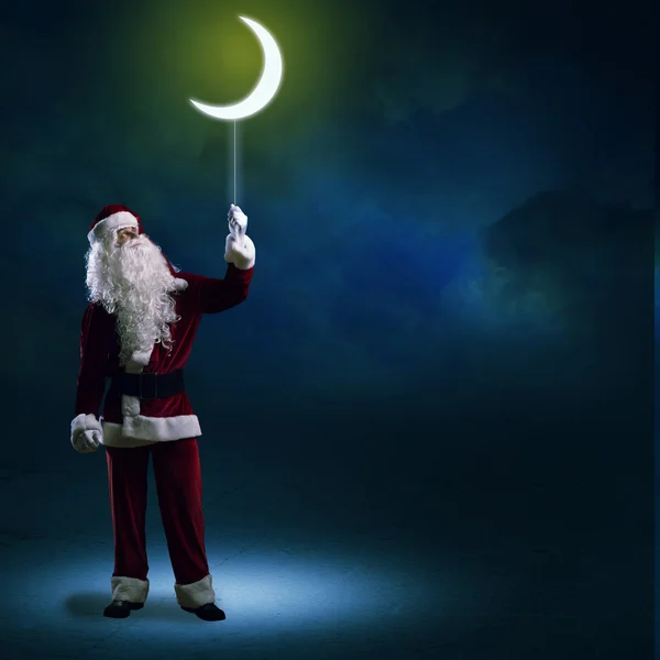 Papai Noel segurando uma lua brilhante — Fotografia de Stock