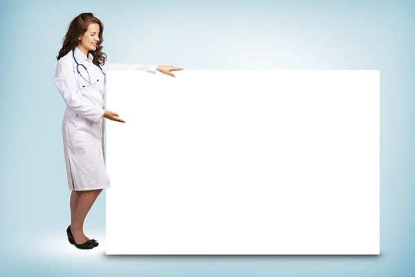 Jovem médico de pé perto de um banner em branco — Fotografia de Stock