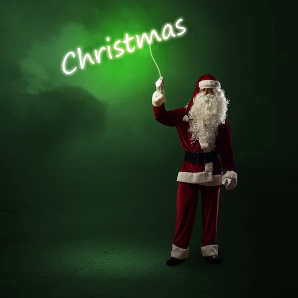 Weihnachtsmann hält ein leuchtendes Weihnachtswort in der Hand — Stockfoto