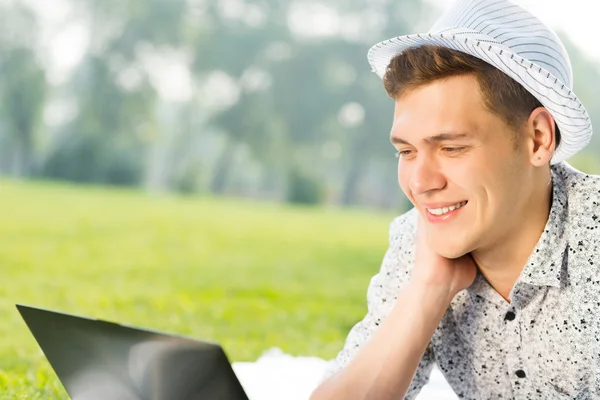 Giovane che lavora nel parco con un computer portatile — Foto Stock