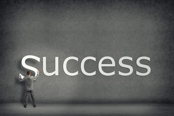 Businessman collects on the wall the word success — Stock Photo, Image