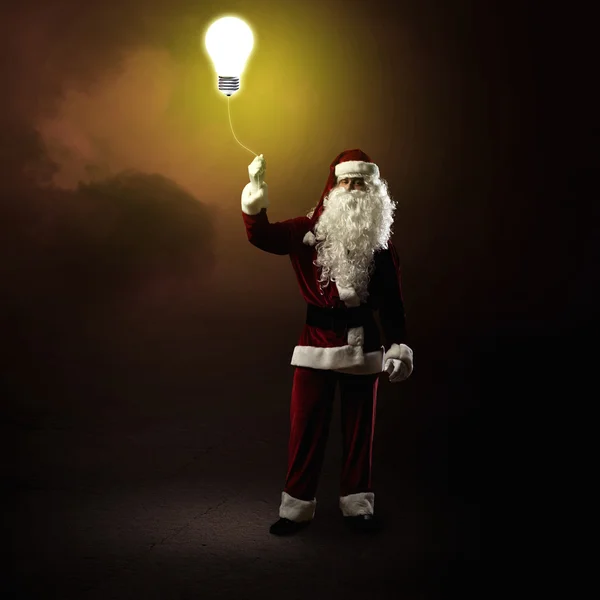 Санта Клаус держит сияющую лампу — стоковое фото