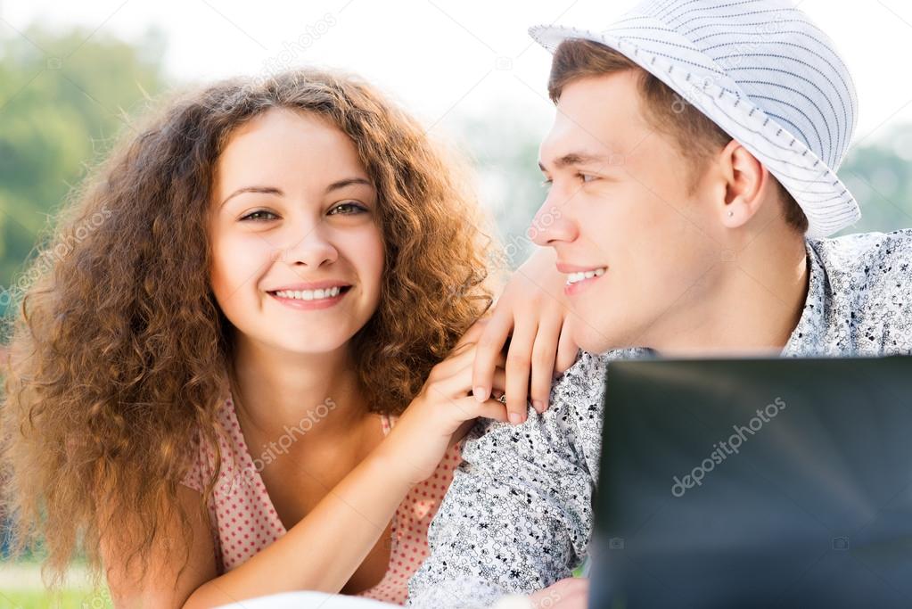 couple lying together in a park with laptop