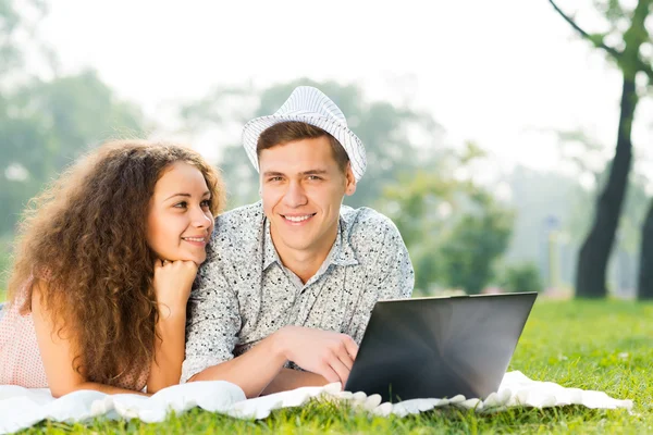 Paar liegt mit Laptop zusammen im Park — Stockfoto