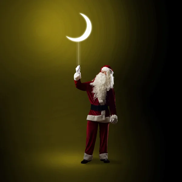 Santa claus innehar en lysande måne — Stockfoto