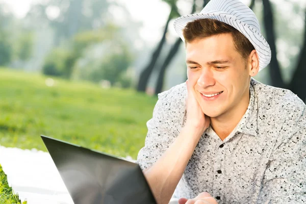 Giovane che lavora nel parco con un computer portatile — Foto Stock