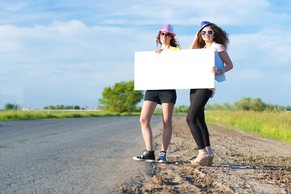 Two young women stand with a blank banner — Stock Photo, Image