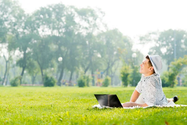 Giovane che lavora nel parco con un computer portatile — Foto Stock