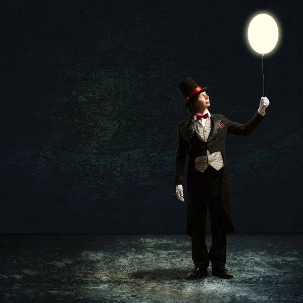 Magician holding a glowing balloon Stock Image