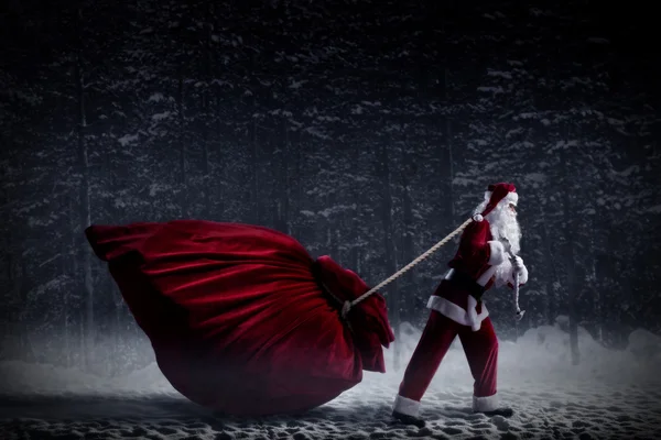 Santa claus táhne obrovský pytel dárků — Stock fotografie