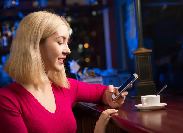 Kvinna med en kopp kaffe och mobiltelefon — Stockfoto