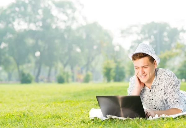 Giovane che lavora nel parco con un computer portatile — Foto Stock