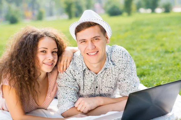 Coppia sdraiata insieme in un parco con laptop — Foto Stock