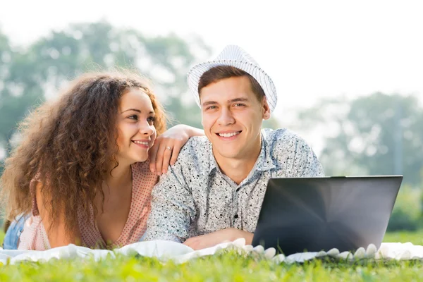 Paar liggen samen in een park met laptop — Stockfoto