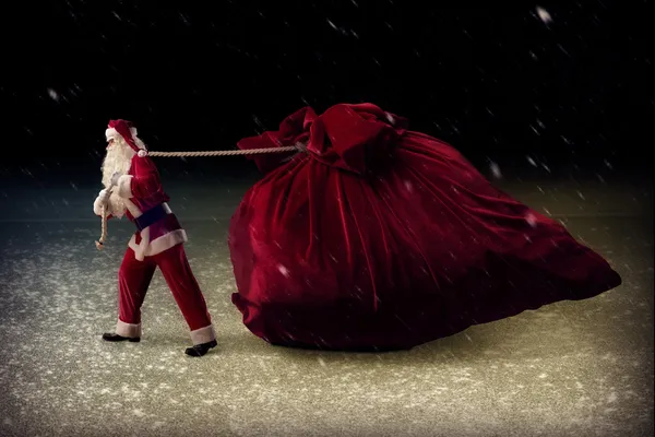 Santa Claus pulls a huge bag of gifts — Stock Photo, Image