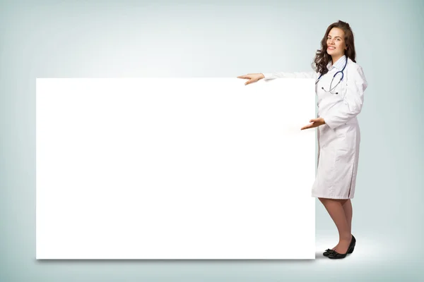 Médico em pé perto de um banner em branco — Fotografia de Stock