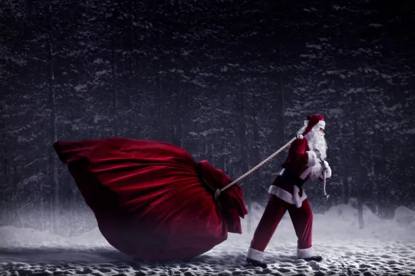 Weihnachtsmann zieht eine riesige Tüte voller Geschenke — Stockfoto
