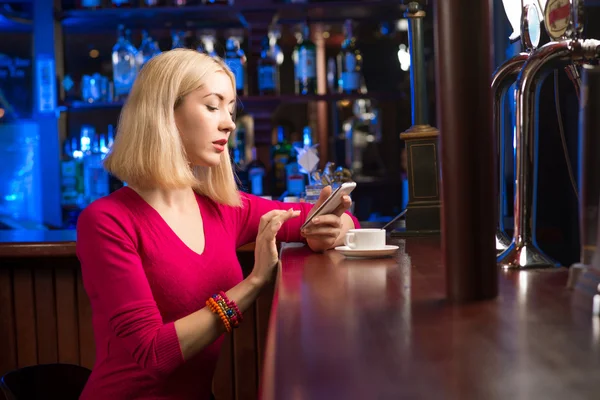 Kvinne med kopp kaffe og mobiltelefon – stockfoto