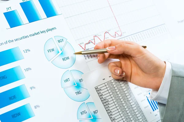 Female hand pointing pen on financial charts — Stock Photo, Image