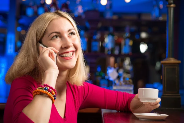 Женщина с чашкой кофе и сотовым телефоном — стоковое фото