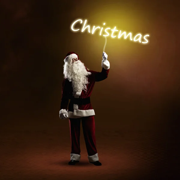 Santa Claus is holding a shining Christmas word — Stock Photo, Image