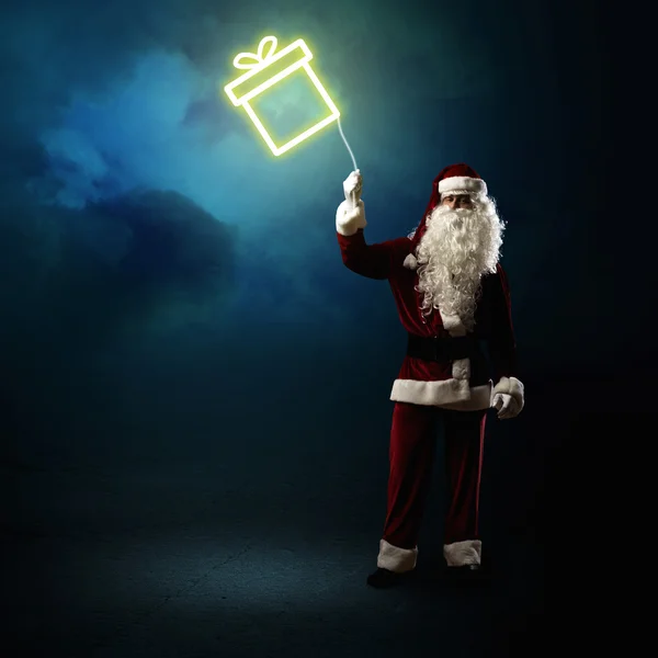 Santa claus drží zářící dárek — Stock fotografie