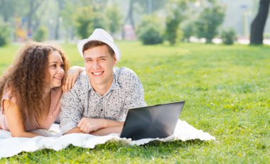 Çift birlikte parkta laptop ile yalan