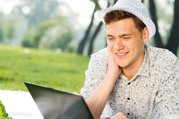 Giovane che lavora nel parco con un computer portatile — Foto Stock