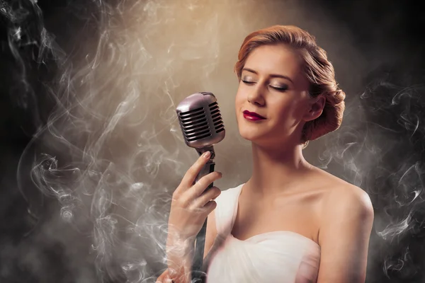 Piękna blond kobieta piosenkarka z mikrofonem — Zdjęcie stockowe