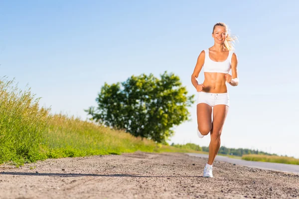 Giovane donna atletica che corre sulla strada — Foto Stock