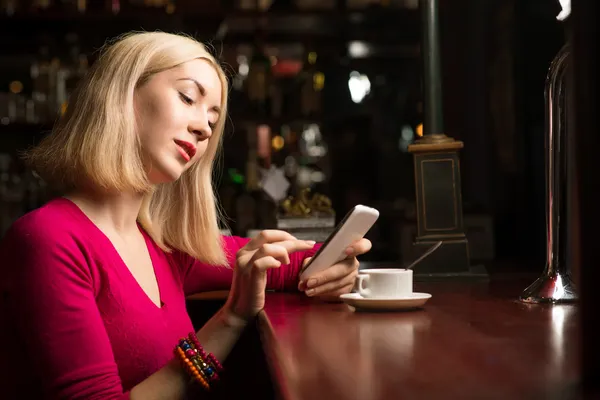 Mujer con una taza de café y teléfono celular —  Fotos de Stock