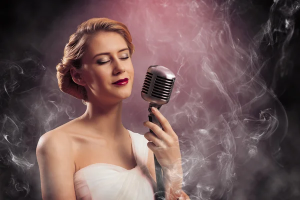 Mooie blonde vrouw zangeres met een microfoon — Stockfoto