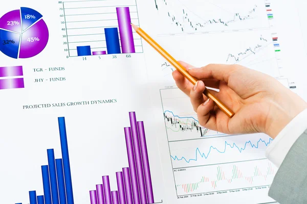 Female hand pointing pencil on financial charts — Stock Photo, Image