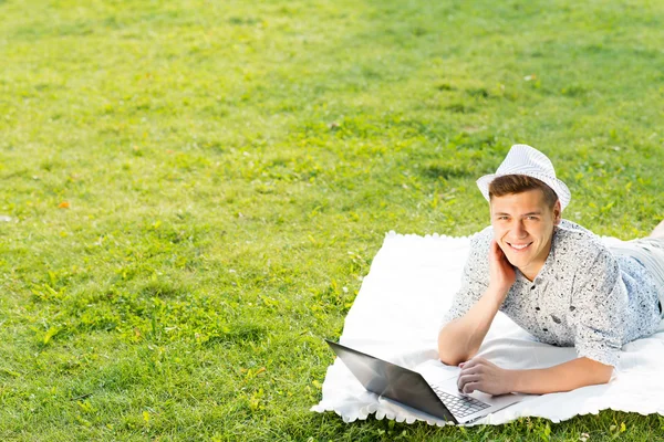 Young man working in the park with a laptop — Stock Photo, Image